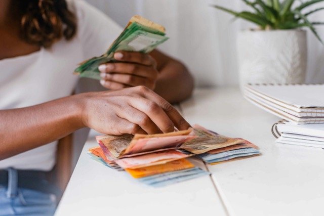 a person sitting at a table with stacks of money after reading how to claim two pot